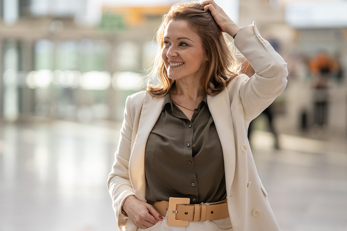 A woman smiling and putting her hand on her head while at an office building after getting BOTOX in Sequim.